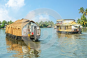 Indian traditional houseboats floating on Pamba river, with palms at the coastline, Alappuzha, Kerala, South India