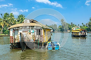 Indian traditional houseboats floating on Pamba river, with palms at the coastline, Alappuzha, Kerala, South India