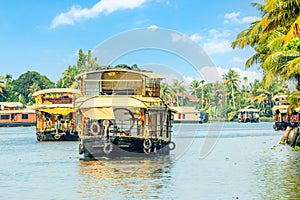 Indian traditional houseboats floating on Pamba river, with palms at the coastline, Alappuzha, Kerala, South India