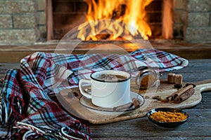 Indian traditional Masala chai tea in a mug, cinnamon sticks and anise, before cozy fireplace. Stay at home and drink a healthy