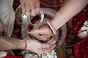 Indian traditional wedding. authentic Vedic wedding ritual called vivaha Yajna. Red Sari, women hands with mehendi close