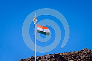 Indian tricolor national flag on a flagpole, waving in wind on mountain top. Blue sky background. Isilated Close up. 26 January