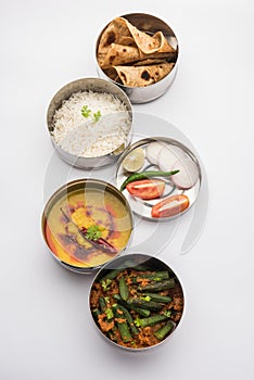 Indian Lunch box or tiffin - Spicy Ladies Finger, dal fry, rice and chapati photo