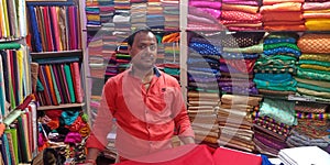 an indian village clothes shopkeeper standing inside the store in India