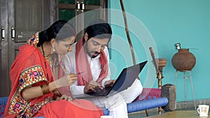 Indian village couple doing card payment using laptop - online shopping concept