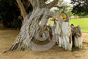 Indian village god of horse statues with old tree at a village temple complex.