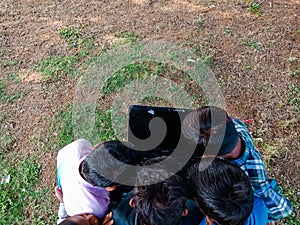 Indian village poor kids watching laptop together on group at natural field in india January 2020