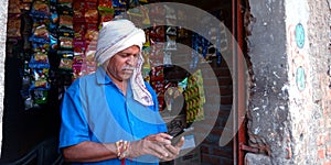 An indian village shopkeeper operating 4G mobile at shop