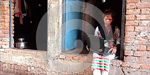 An indian villager teen operating laptop computer seating at corridor