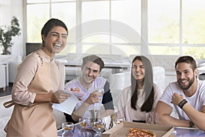 Indian waitress laughing with restaurant guests, group of young people