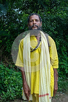 An Indian wanderer monk in a traditional yellow dress stands in a special posture