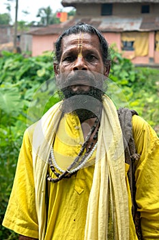 An Indian wanderer monk in a traditional yellow dress stands in a special posture