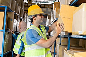 Indian warehouse worker put cardboard box in shelf