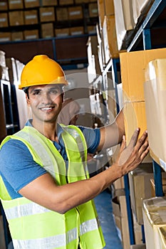 Indian warehouse worker put cardboard box in shelf