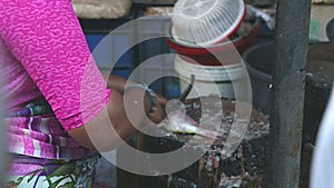 Indian woman cleaning fish at a market stand in Mumbai.