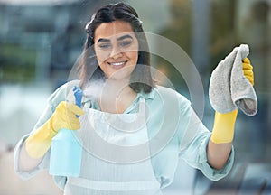 Indian woman and cleaning or glass with spray bottle in home, soap and cloth for hygiene. Female cleaner or worker with