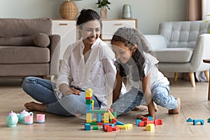 Indian woman and daughter play wooden blocks seated on floor