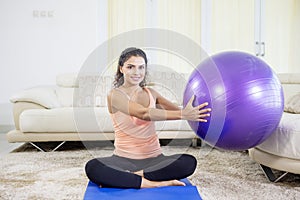 Indian woman doing yoga exercise with pilates ball