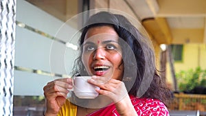 Indian woman drinking masala tea with milk and spices ,she wearing gold earrings and bindi tika on forehead