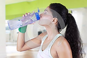 Indian woman drinks water in fitness center