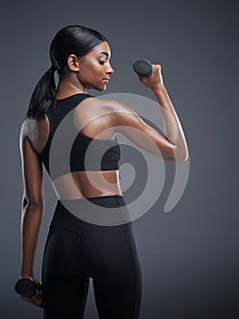Indian woman, dumbbells and workout for fitness in studio on grey background for health, muscles and sportswear. Back