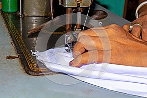 Indian woman hands stitching white cloth with the help of a sewing machine