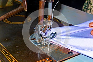 Indian woman hands stitching white cloth with the help of a sewing machine