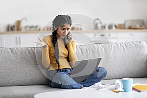 Indian Woman Having Problem With Laptop And Talking On Cellphone At Home