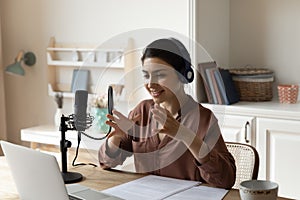 Indian woman in headphones speak using professional microphone by laptop