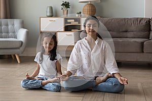 Indian woman her little daughter do meditation practise at home