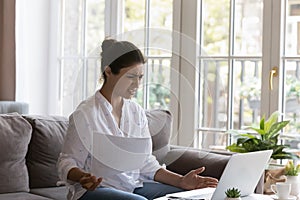 Indian woman holds papers staring at laptop feels angry