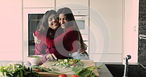 Indian woman hugging mum cooking together healthy food in kitchen