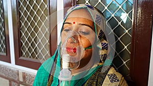 Indian woman infected with Covid 19 disease. Patient inhaling oxygen wearing mask with liquid Oxygen flow