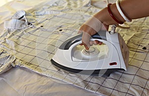 Indian woman ironing clothes using iron on floor after laundry at home. Making household working at home. Laundry service and maid