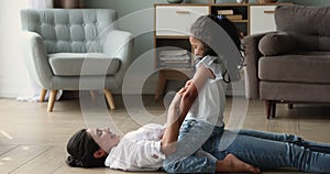 Indian woman lying on floor tickles her little cheery daughter