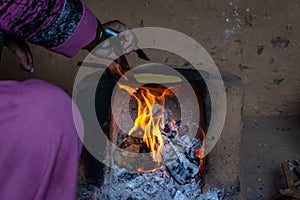 Indian woman making Roti in traditional stove chulha under tough conditions photo