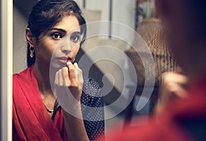 Indian woman putting on a lipstick