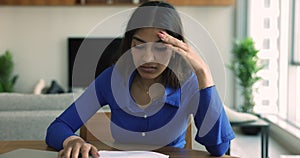 Indian woman sit at desk read bad news feels upset