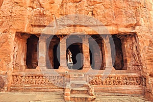 Indian woman standing on stairs to 6th century cave Hindu temple. Old architecture landmark in Badami, India