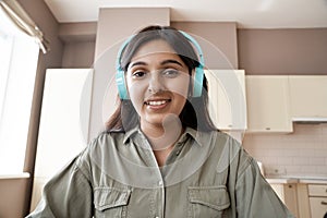 Indian woman student teacher wearing headphones looking at web cam.