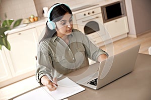 Indian woman student wear headphones watching online class seminar at home.