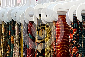 Indian woman traditional dress sarees in display, on hangers in a shop
