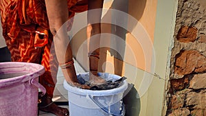 Indian woman washing cloths by hands or manually in plastic water bucket