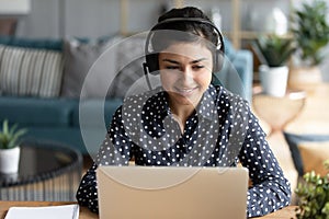 Indian woman wearing headset participates in educational webinar using laptop