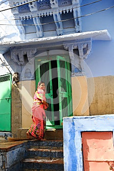 Indian woman wearing sari and smiling in front of her colorful house