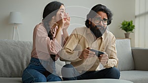 Indian woman wife distract husband from playing virtual game focused Arabian muslim man addicted play tv console