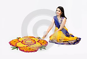 Indian woman or young girl making floral or flower rangoli for diwali or onam, isolated over white background