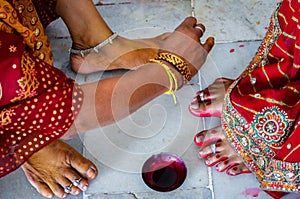Indian women adorning feet with bright red dye Alta mahavar
