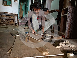 an indian worker making furniture at workshop, iron blade equipment aviable for wood chopping in factory in India January 2020