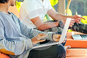 Indian young business people businessman freelancer working outdoors chaise lounge on the beach with laptop.two